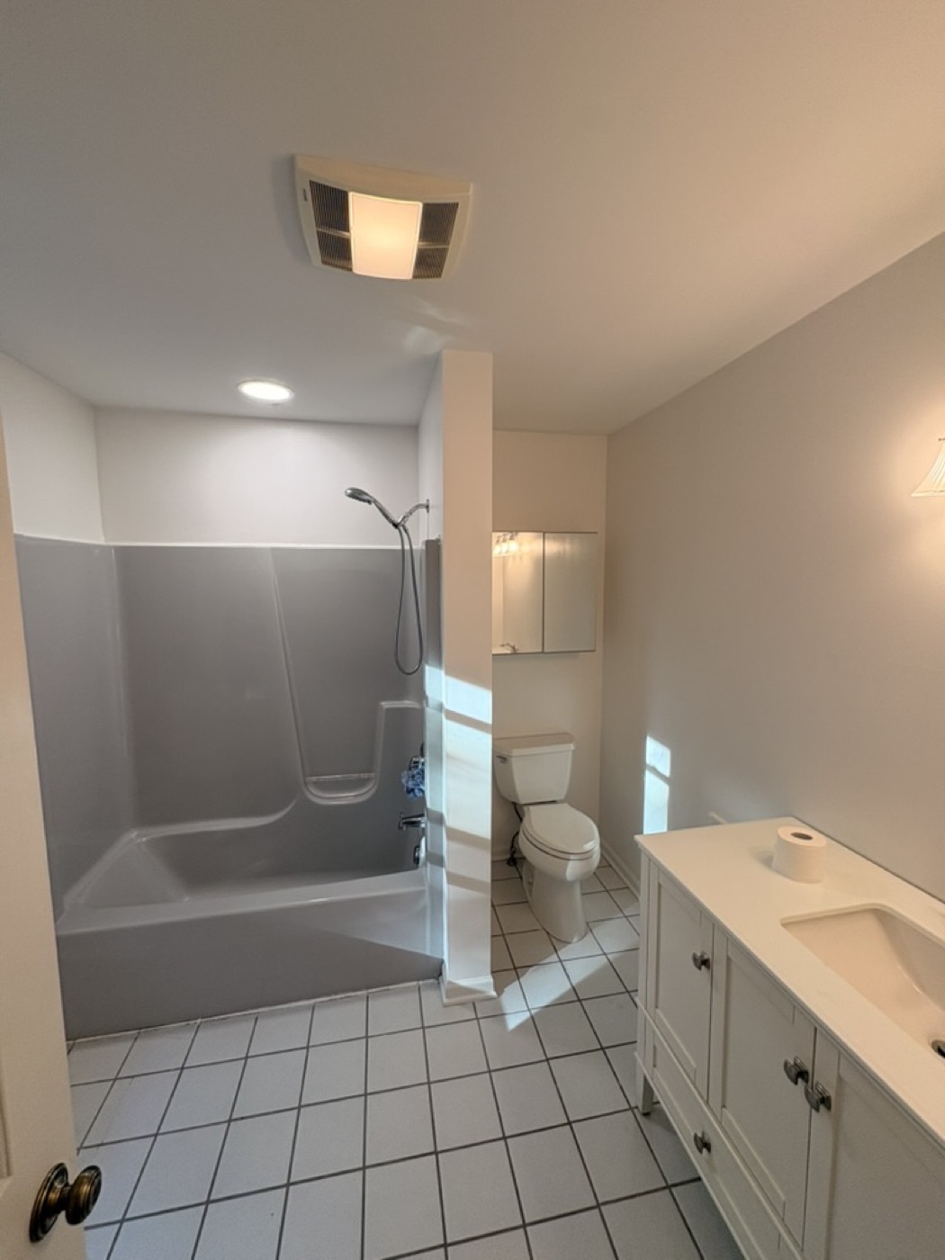 Bathroom with grey painted walls, a tub and white vanity