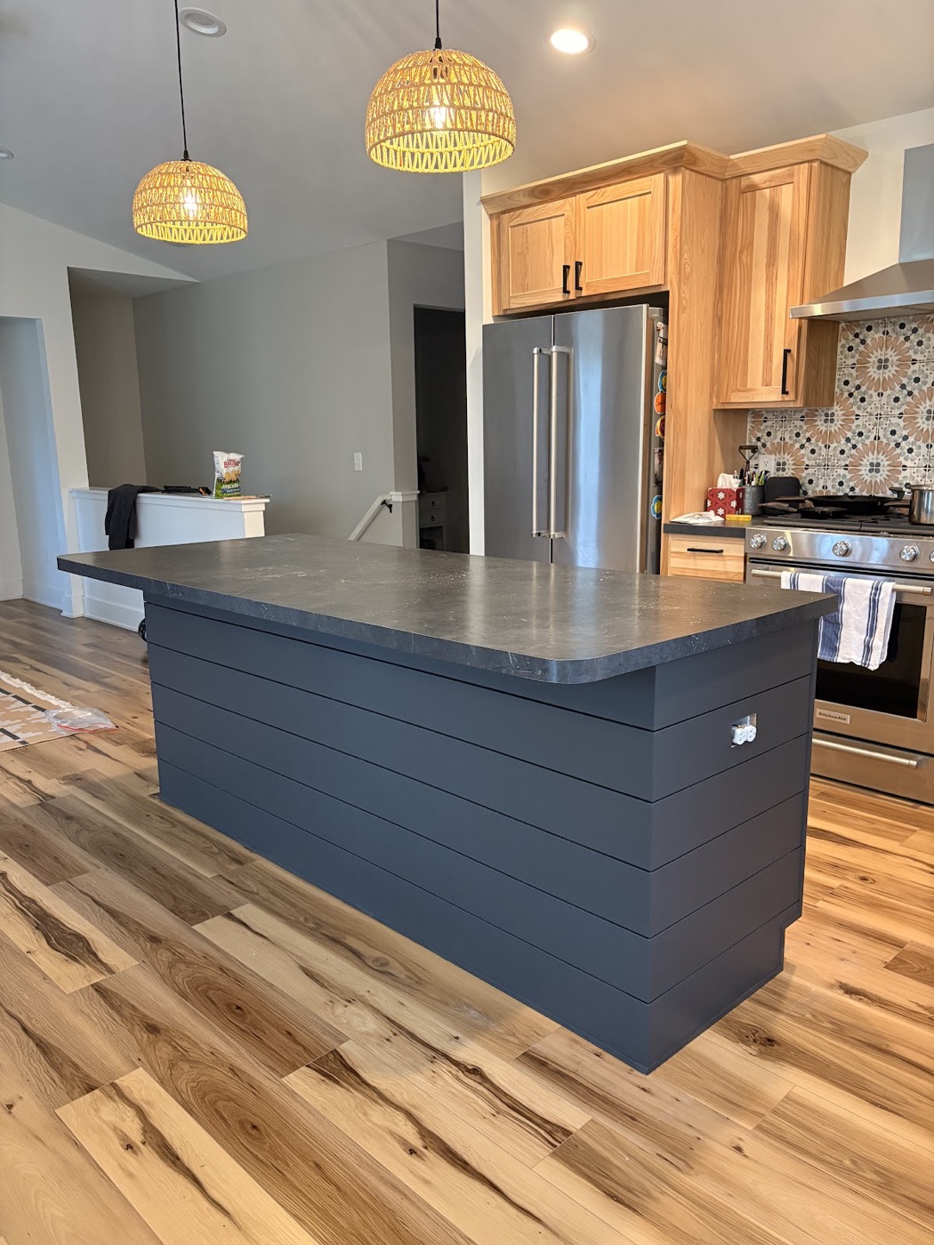 Kitchen with a painted charcoal shiplap-style island and natural wood cabinetry