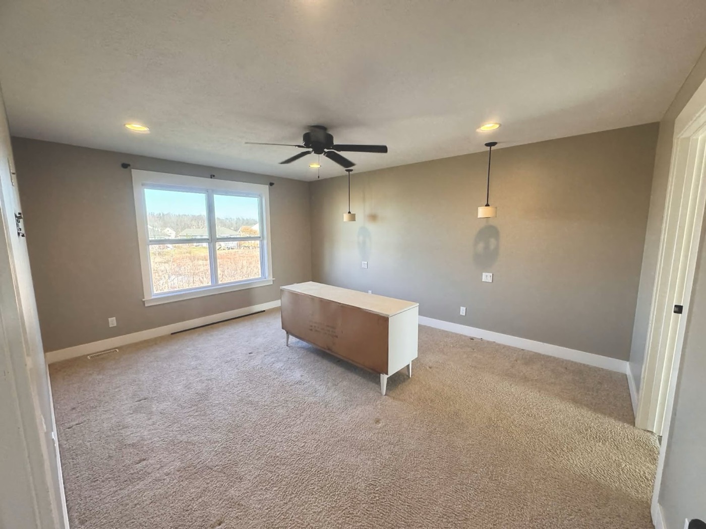 Empty room with taupe painted walls and pendant lighting
