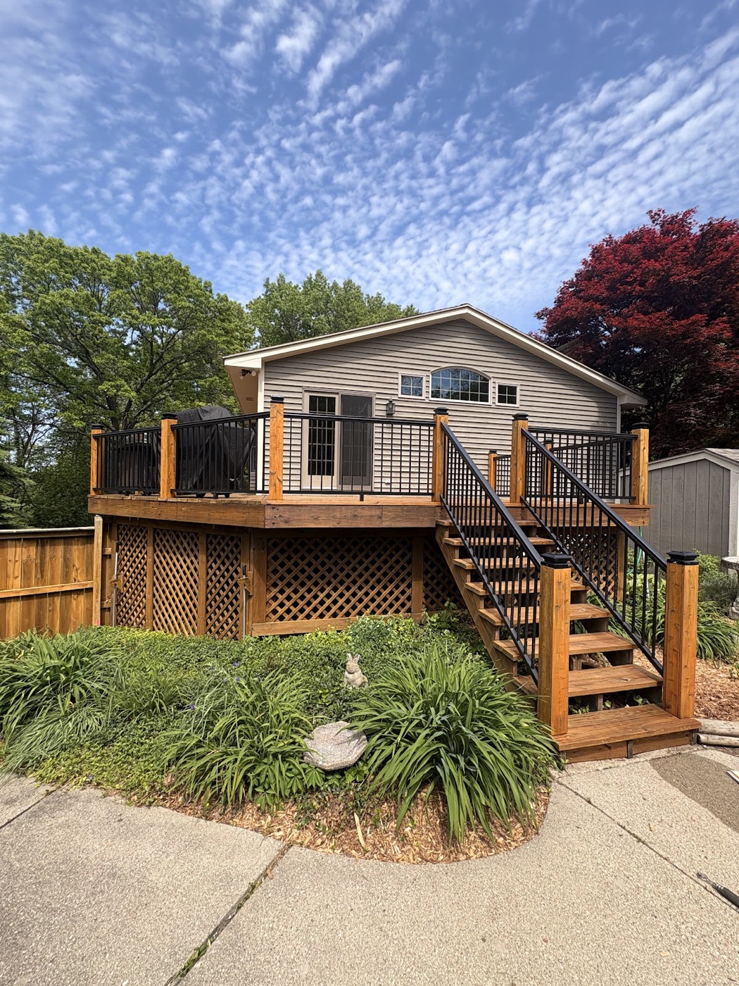 Full exterior view of a house with a stained wood deck and black metal railings