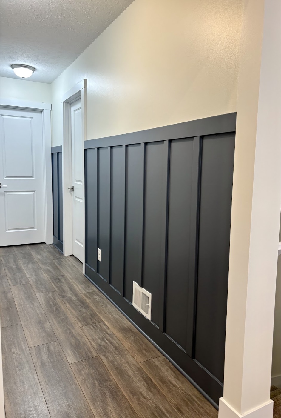 Hallway with a charcoal board-and-batten accent wall and white doors