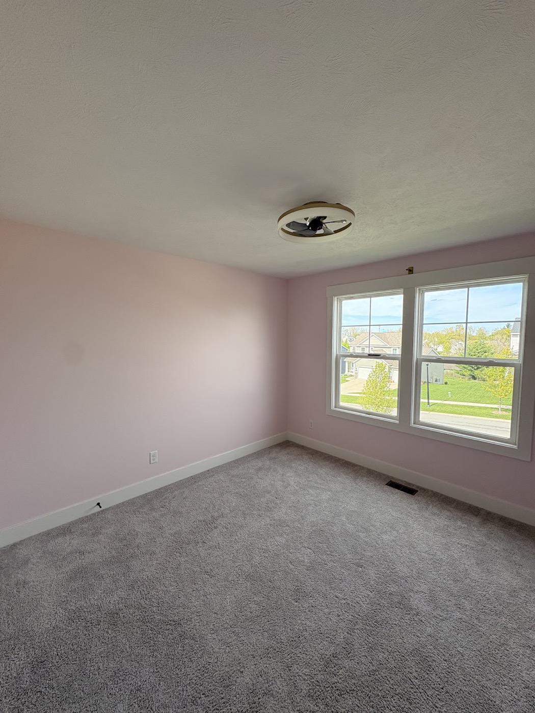 Freshly painted pink accent wall in an empty bedroom with a large window