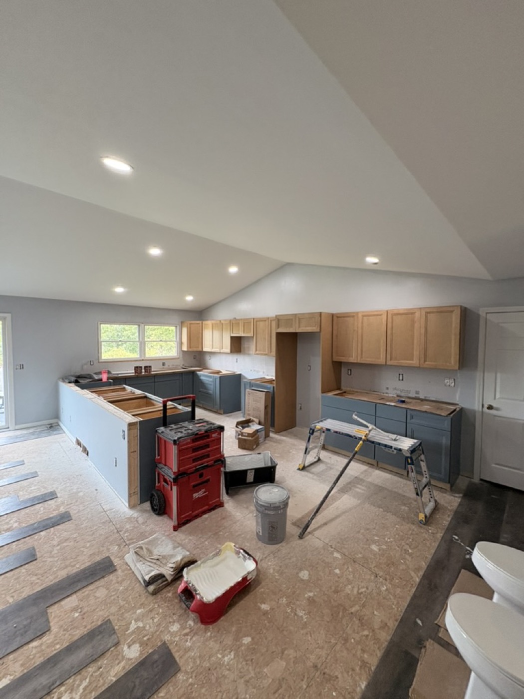 Kitchen under renovation with cabinets installed before painting and tools on the floor