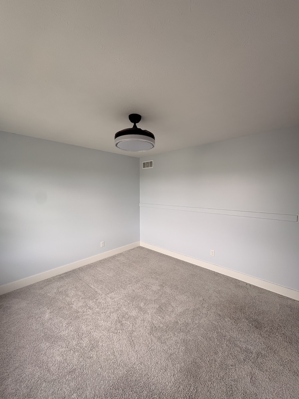 Empty bedroom with light blue-grey painted walls and wainscoting trim