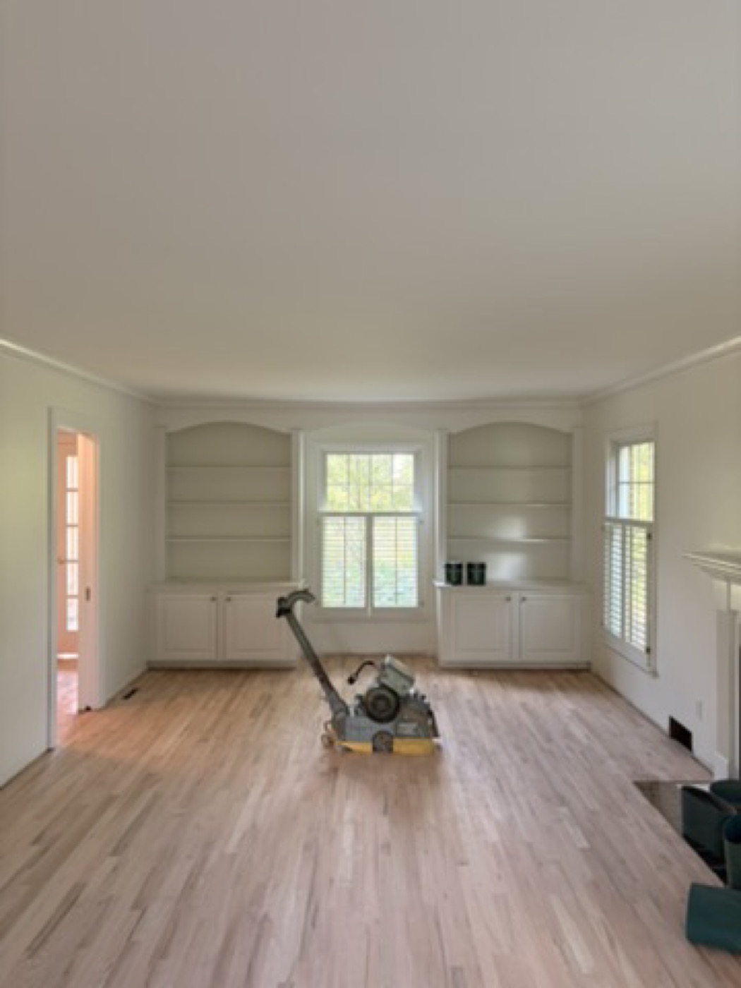 Living room with painted built-ins and a wood stove during floor refinishing