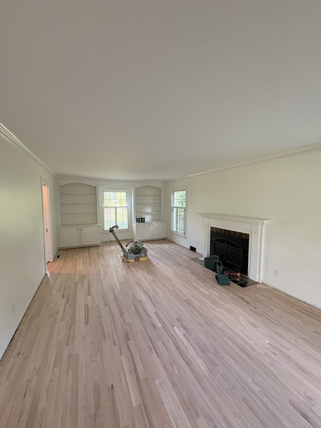 Living room with white painted built-in shelving during floor refinishing