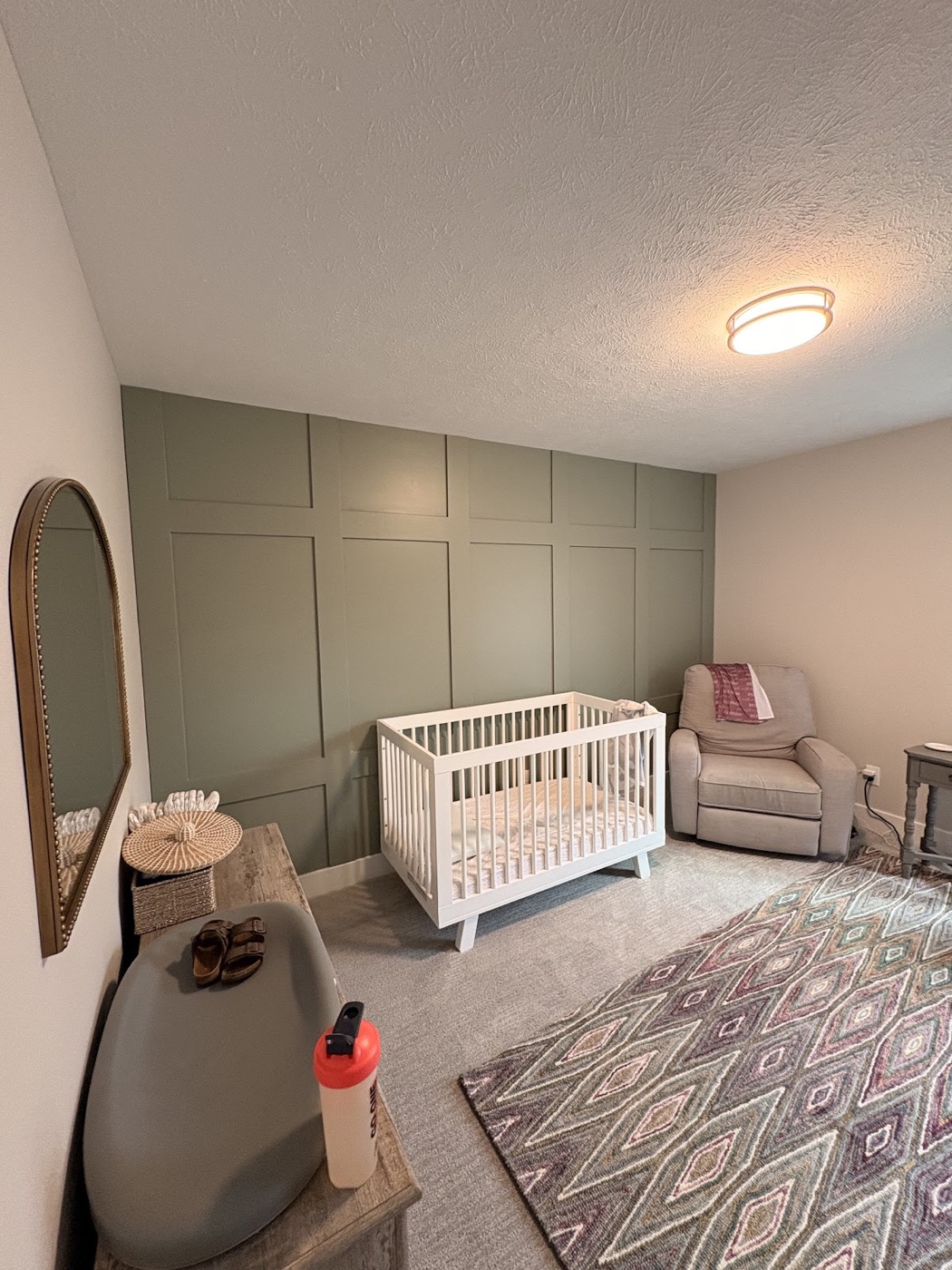 Nursery with a sage green board-and-batten accent wall and white crib