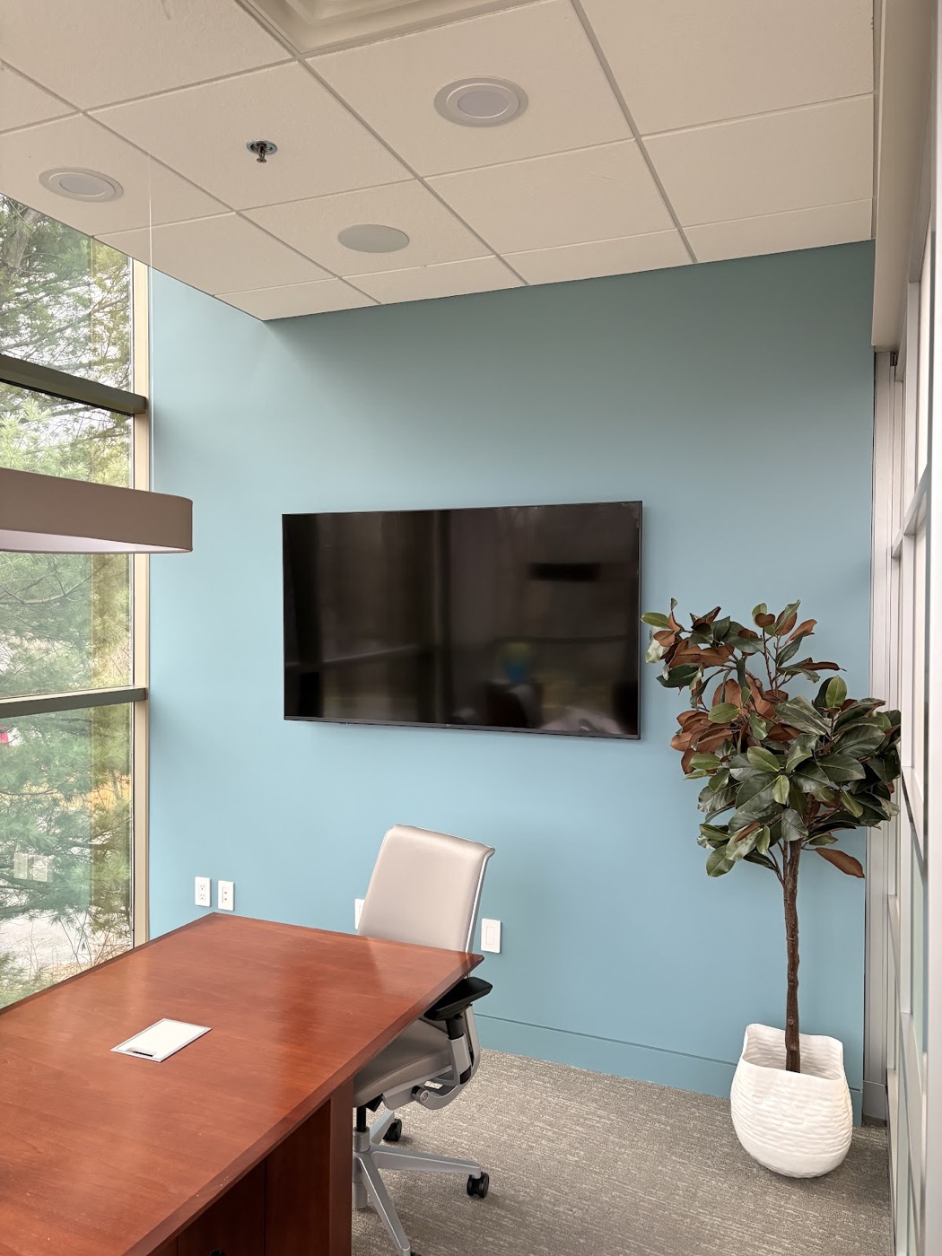 Small office with a painted light blue accent wall and mounted TV