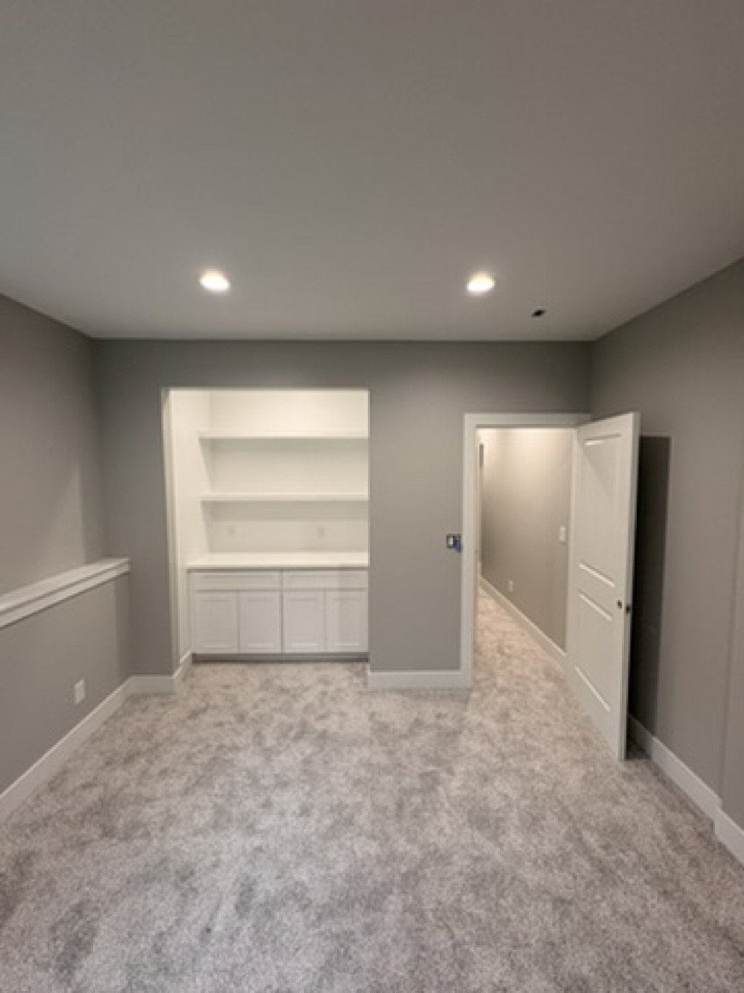 Built-in bookshelf and cabinet painted white in a grey room