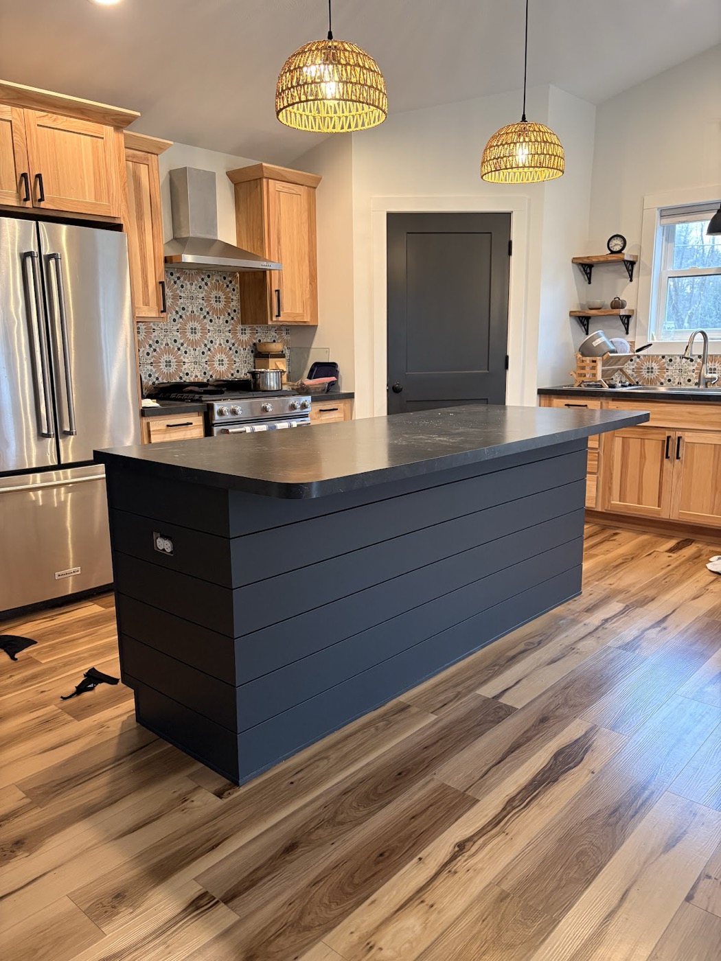 Kitchen with a painted black shiplap-style island alongside natural wood cabinetry