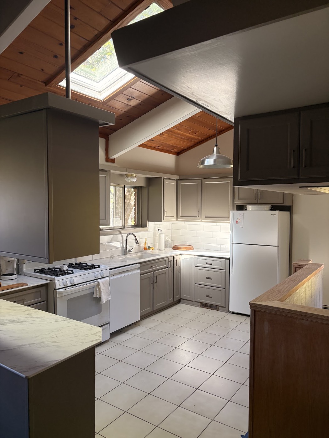 Kitchen with painted taupe cabinets, white subway tile backsplash and a vaulted wood ceiling