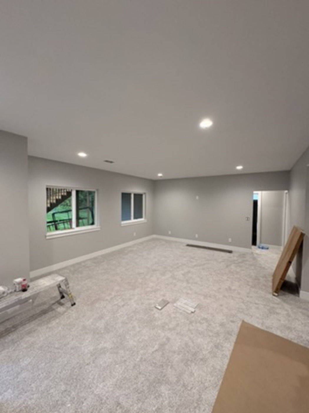 Empty room mid-renovation with carpet, painting supplies and a ladder visible