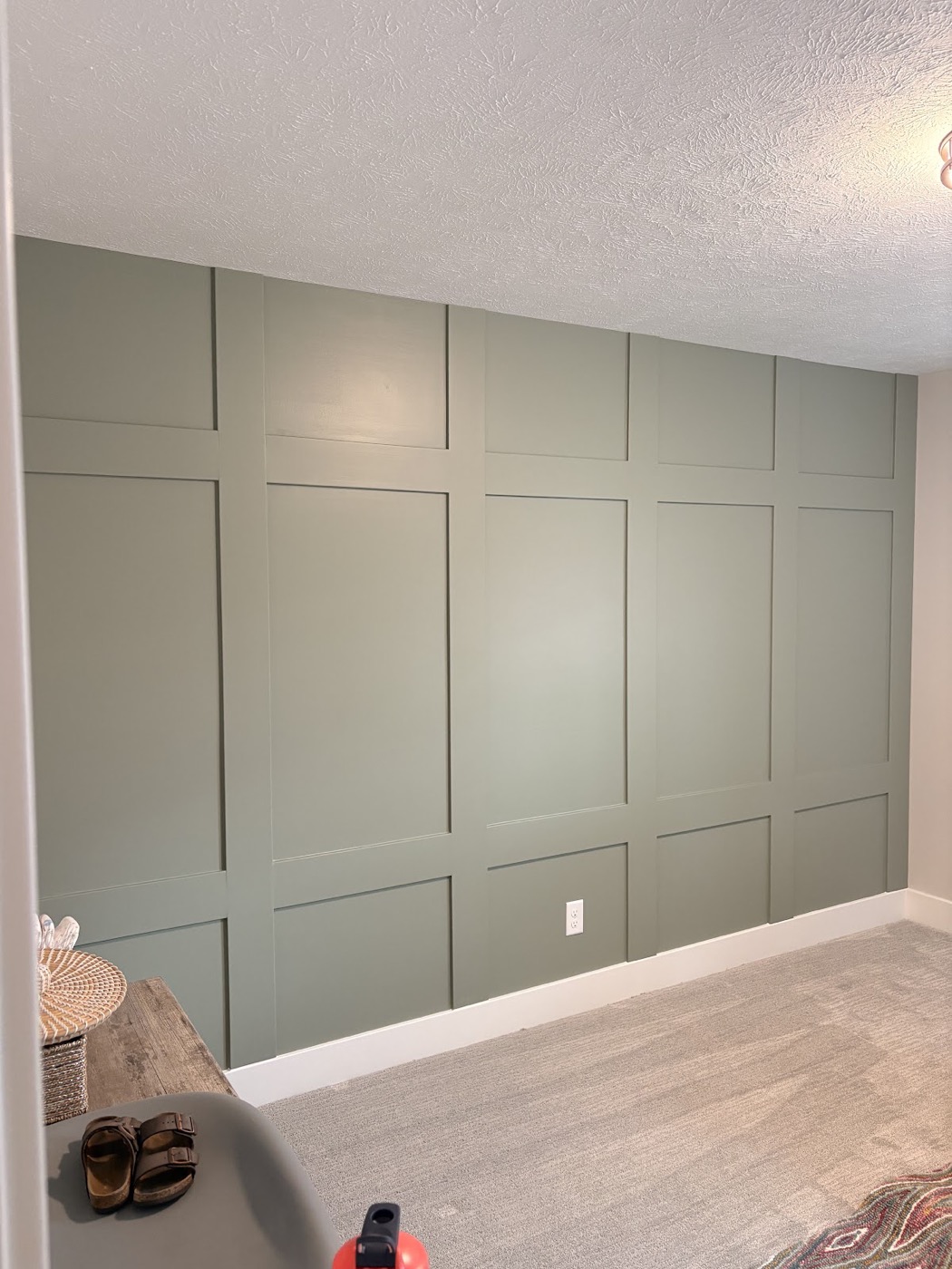 Close view of a sage green board-and-batten accent wall