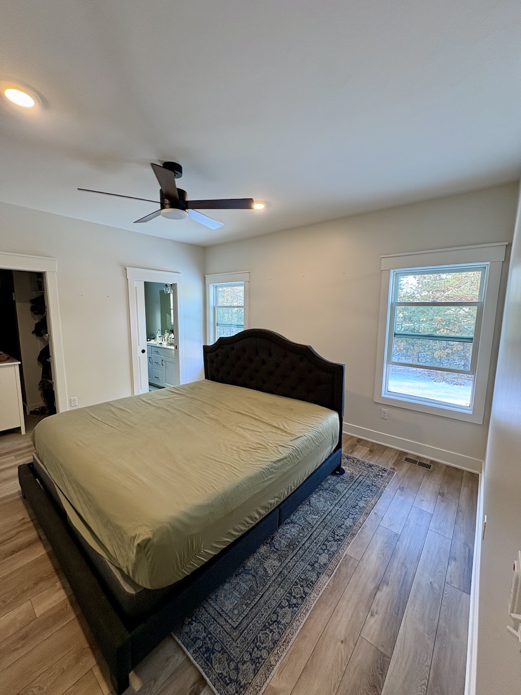 Staged bedroom with a dark upholstered headboard and neutral painted walls